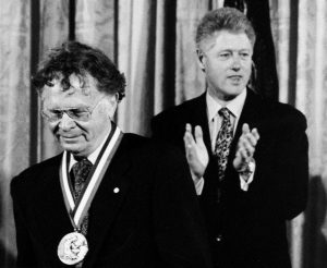 Wallace Broecker wearing a medal with President Bill Clinton clapping behind him. 